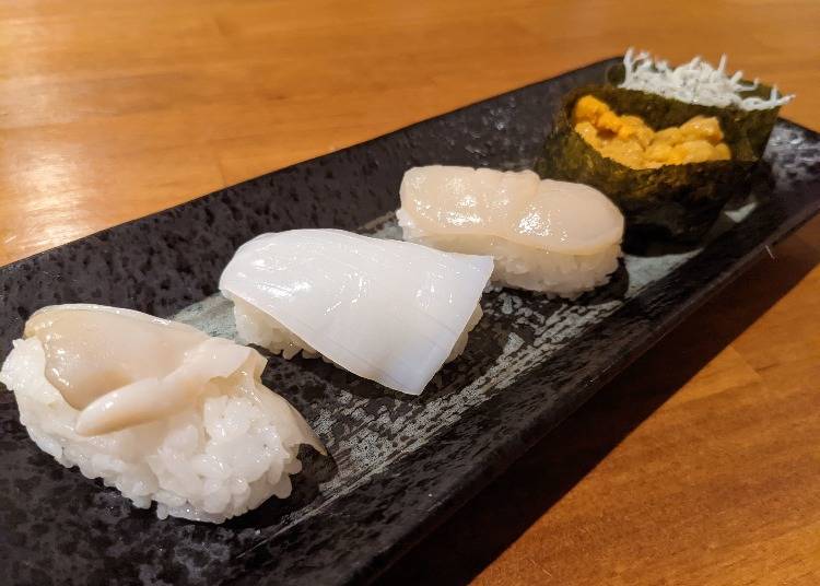 From the bottom left, tsubu gai (whelk), ika (squid), hotate (scallop), uni (sea urchin) shirasu gunkan (whitebait gunkan sushi)